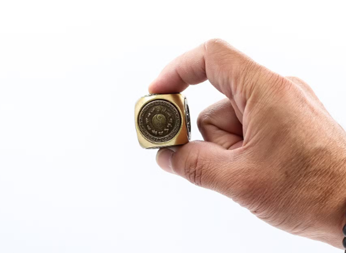 Talizman „Kostka Harmonii” – niewielka mosiężna kostka o wymiarach 3 × 3 cm trzymana w dłoni